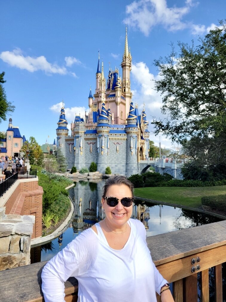 Woman smiling in front of lake and Cinderella Castle at Magic Kingdom