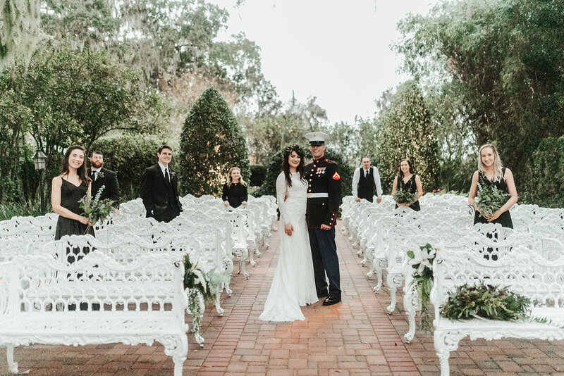 a bride and groom  standing in their outdoor ceremony site surrounded by bridesmaids and groomsmen