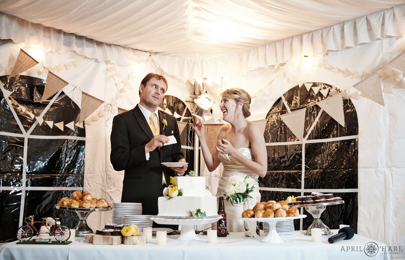 Couple cuts cake in the white tent at Wedgewood on Boulder Creek with the sides of the tent on
