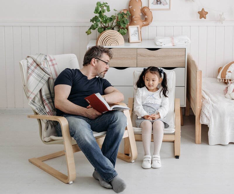 homeschool father in rocker reading story to preschool student