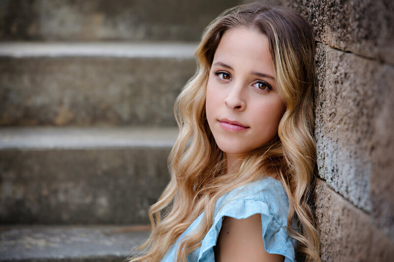 Radiant HS Senior photographed in Ballantyne wearing a cute blue dress and sitting on a concrete staircase