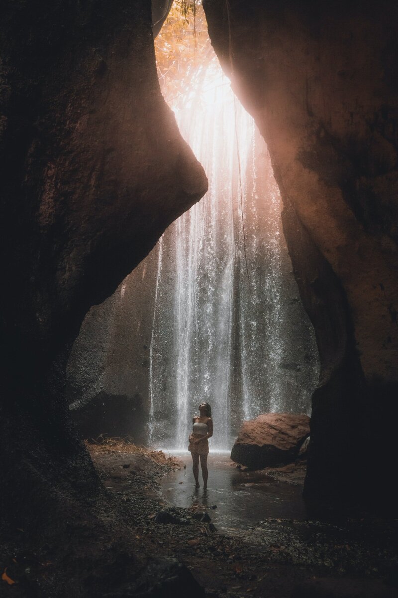 woman stood underneath waterfall