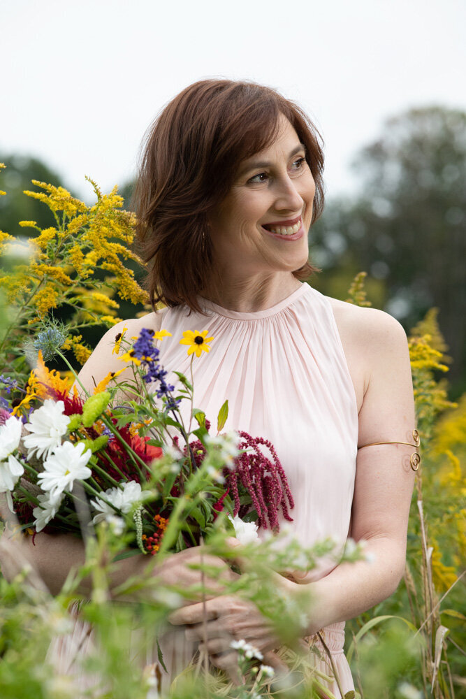Jennifer Hendler smiling softly to the right in a flower field