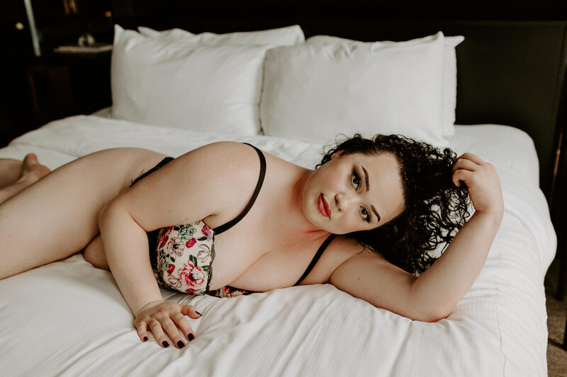 plus size woman laying on a bed in floral lingerie