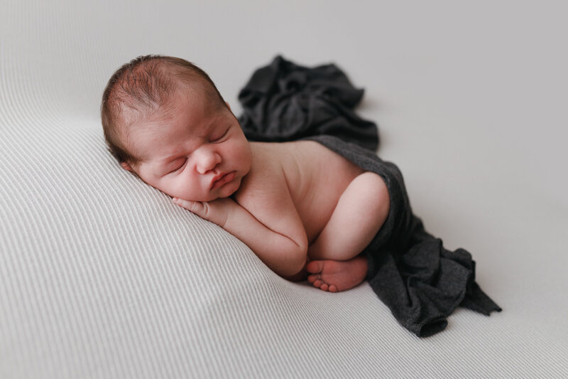 newborn baby boy sleeping with white backdround and blue wrap