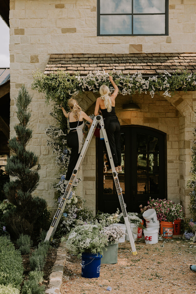 Two Nashville floral designers on a ladder working on a wedding ceremony feature
