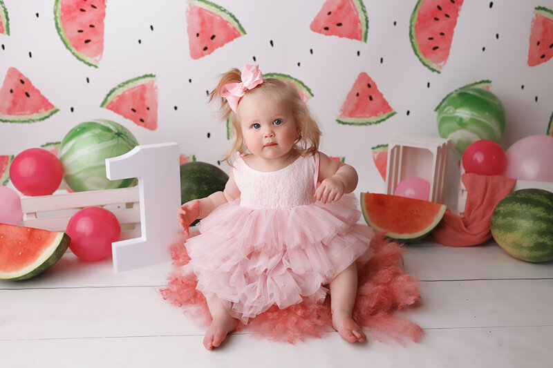baby girl during her birthday photograph session  sitting with number 1 and watermelons