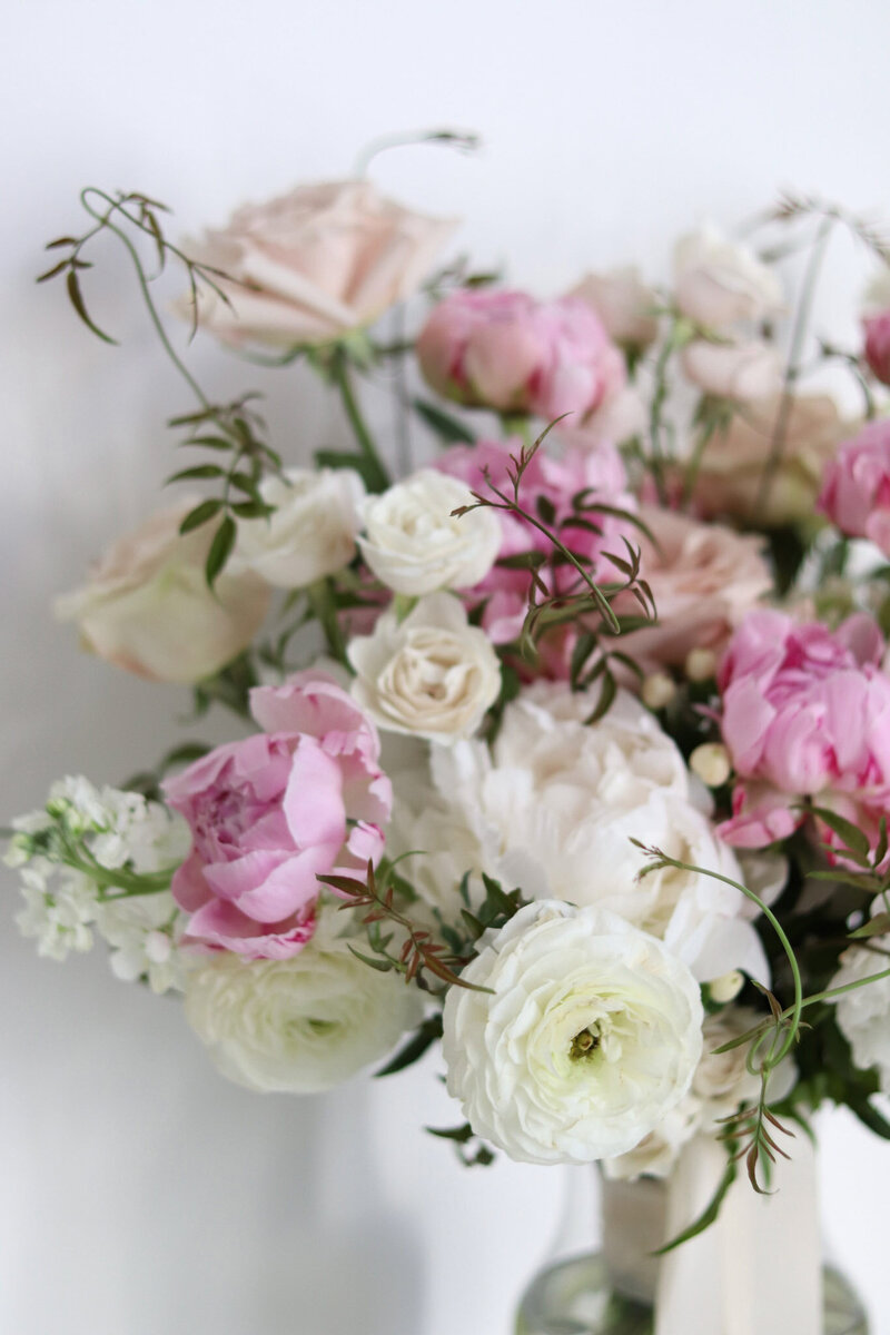 Blush and white romantic wedding bouquet with peonies, roses, ranunculus, and jasmine.