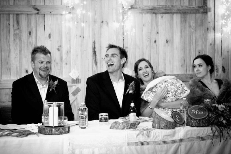 Wedding couple laughing at their table during wedding reception speech