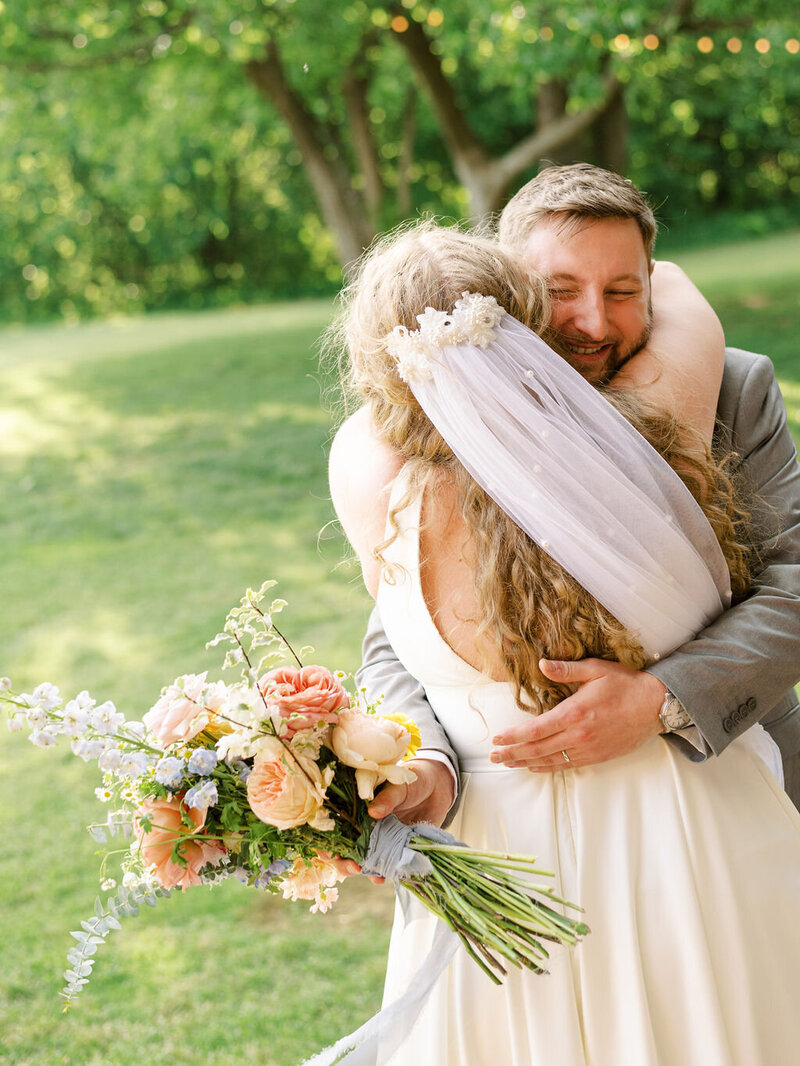 A candid image of a bride and groom hugging right after their wedding ceremony.
