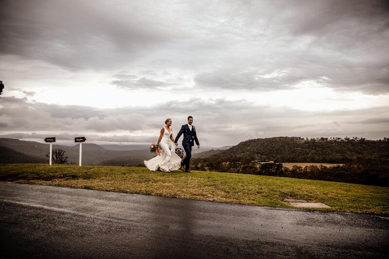 Wedding couple walking on the green field under beautiful storm clouds
