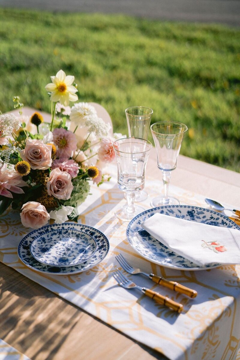 Colorful blush yellow and white compote arrangement with blue and white patterned china plates