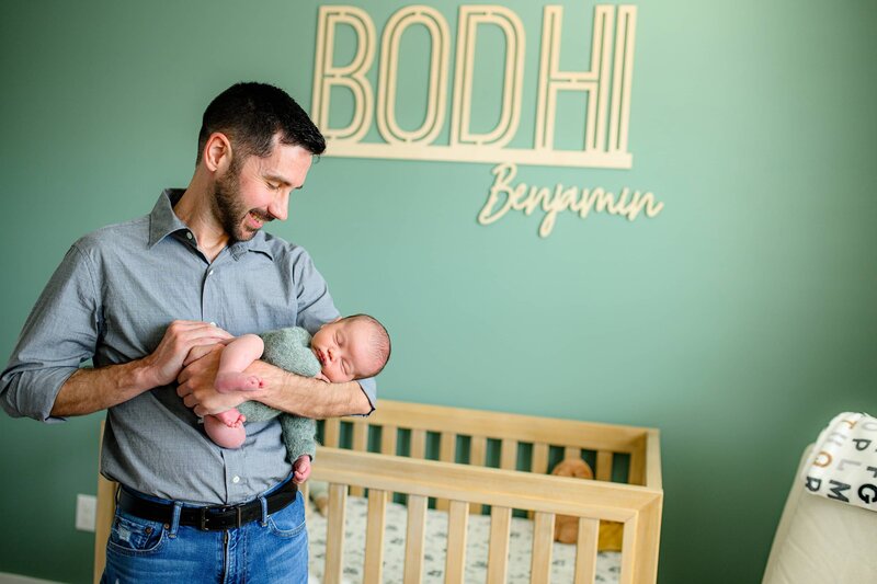 father holds his son dressed in a knit outfit while looking down at him