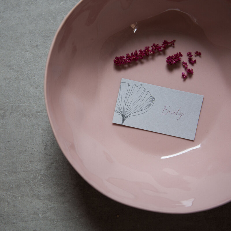 Flat grey wedding place card or name card sitting in a pink bowl