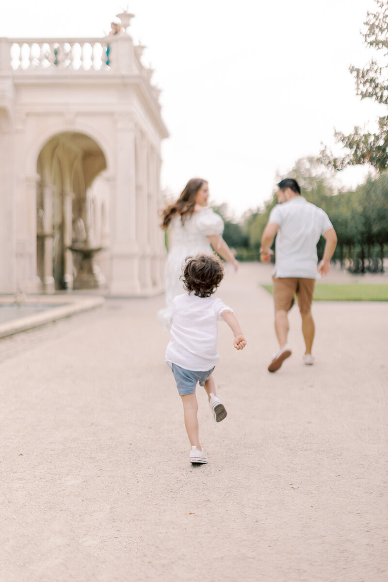 Young boy chases his parents during outdoors Philadelphia family portrait session