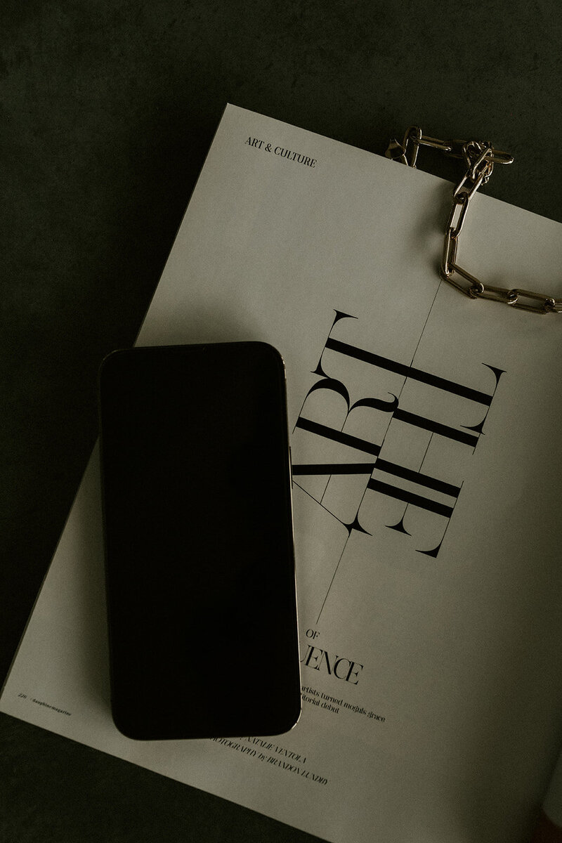 Phone sitting on a paper with "The Art of Opulence"