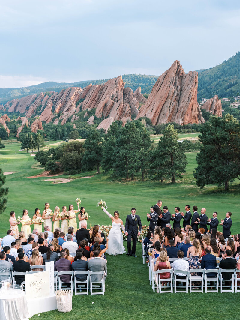 A colorful bride's rainbow bouquet of flowers with her bridesmaids photographed by Colorado Wedding Photographer JKG Photography