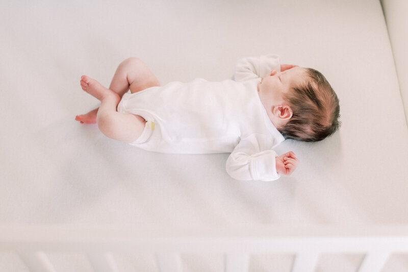 A newborn baby lays in her crib during her newborn session
