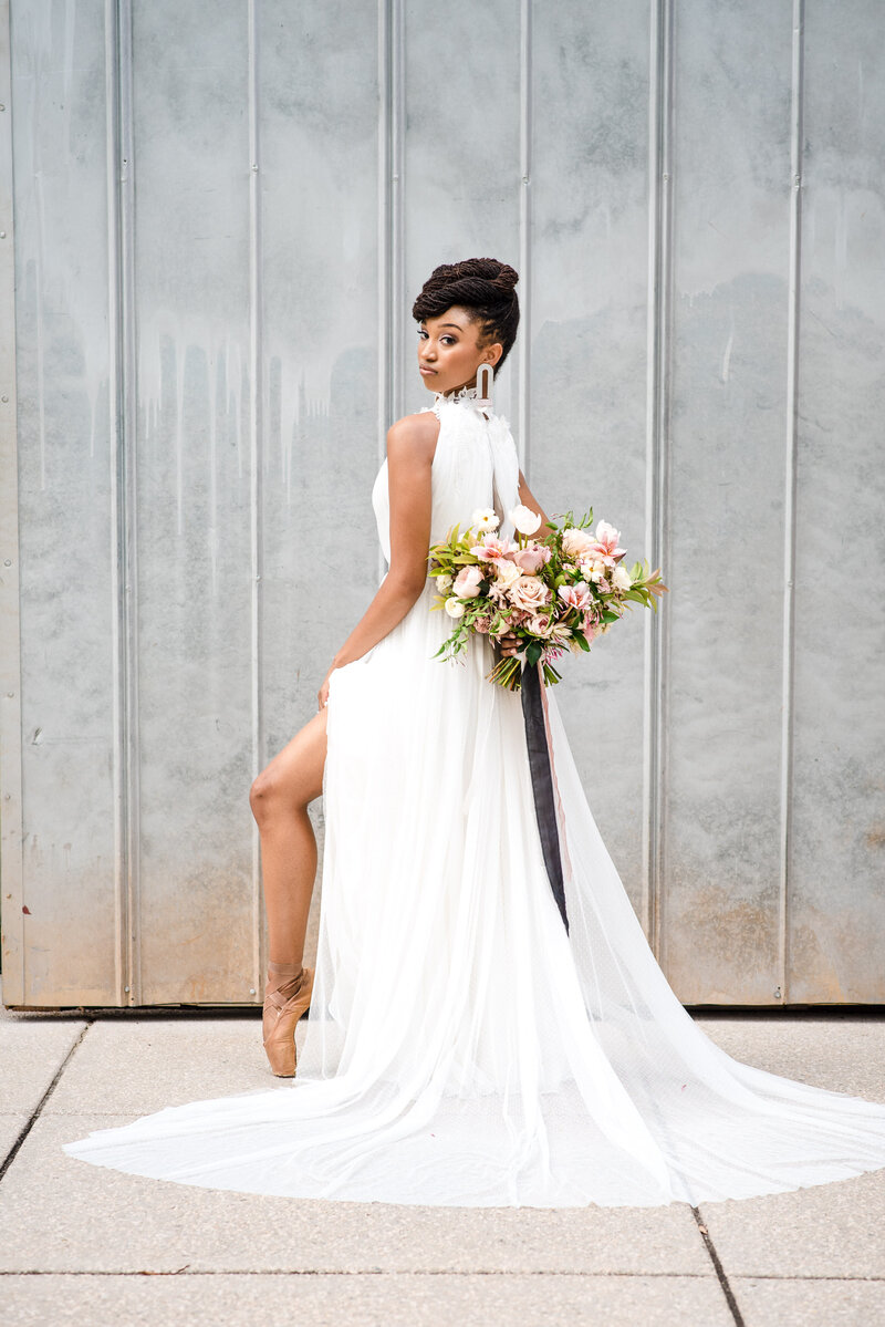 Black-bride-turned-away-from-camera-showing-off-back-of-dress-and-ballet-shoes-through-slit-in-dress-at-North-Corner-Haven