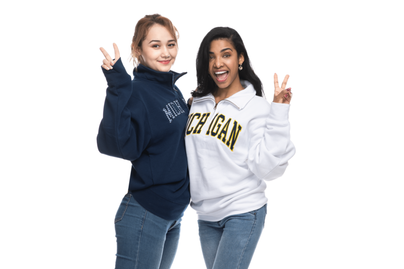 Two female models wearing different Michigan half zip pullover sweatshirts in white and blue