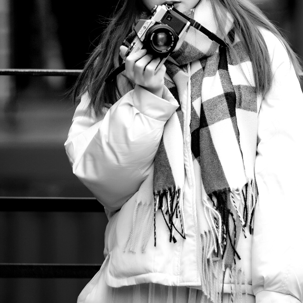 girl in thick winter coat and scarf holding a minolta film camera