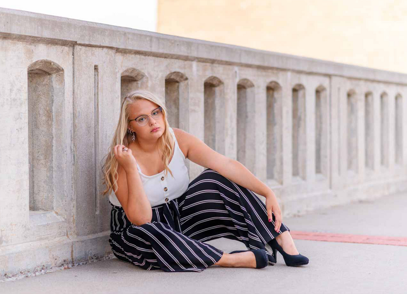 high school senior girl sitting on sidewalk bridge in lowell michigan