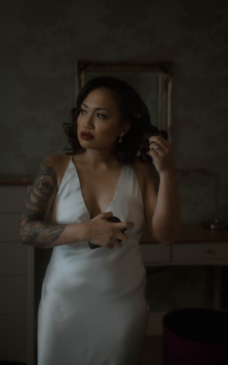 Bride gently touching her hair, captured in a quiet, elegant moment of preparation, radiating beauty and grace as she gets ready for her wedding day