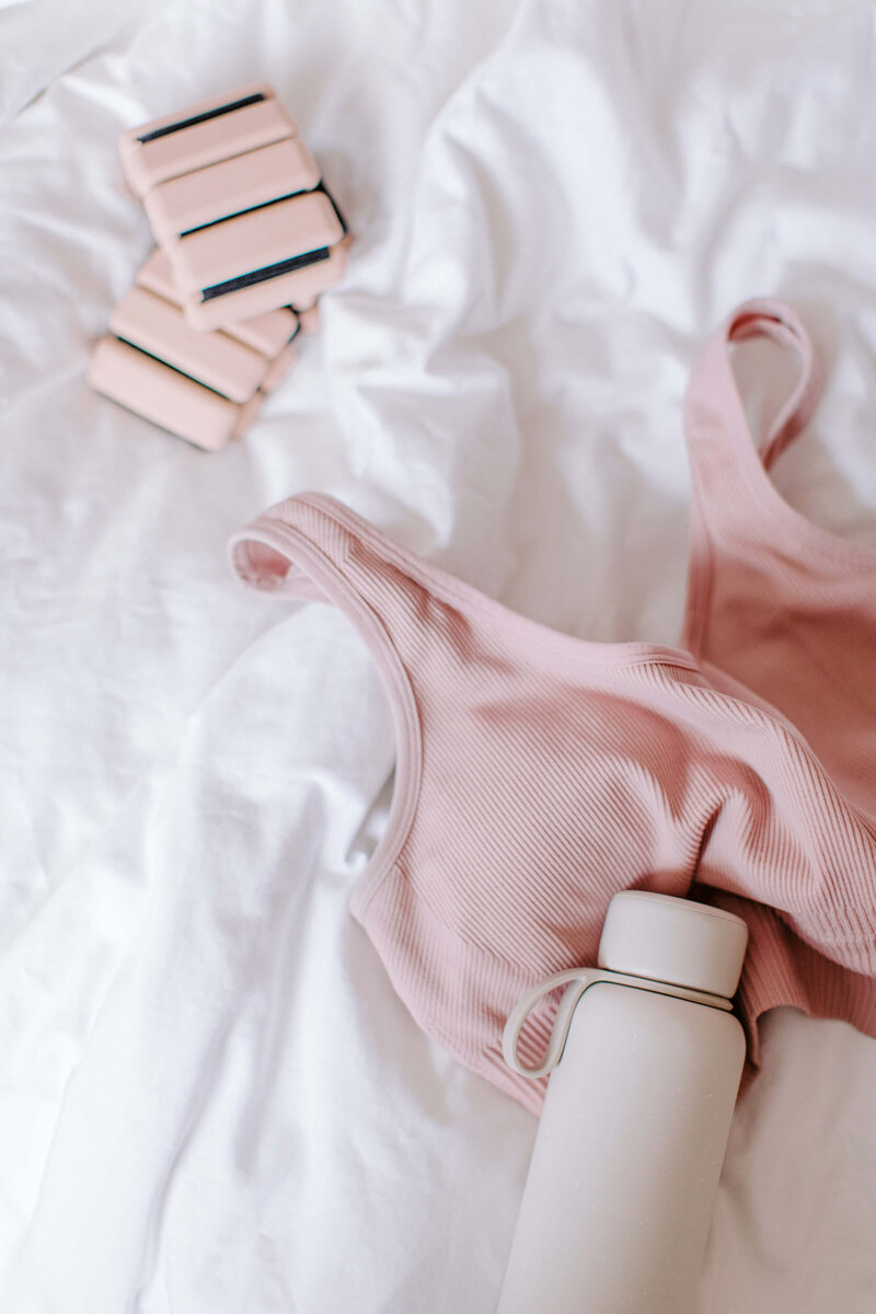 blush pink sports bra and neutral water bottle  with weights
