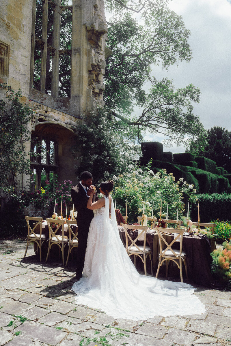 Bride and groom standing beside an elegant outdoor reception setup at Sudeley Castle, captured in a romantic, cinematic style by a luxury documentary wedding photographer UK.