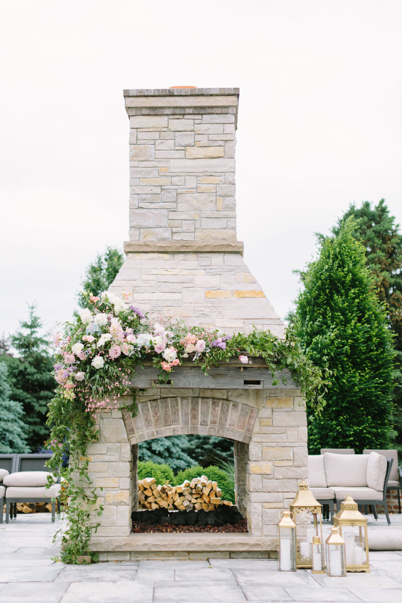 Outdoor wedding reception with flowers and candles by fireplace