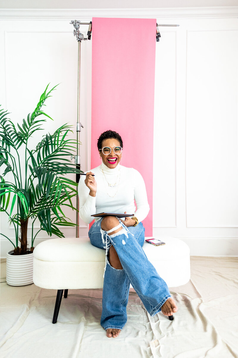 black woman with teenie weenie afro, white glasses and pink lipstick smiling at the camera