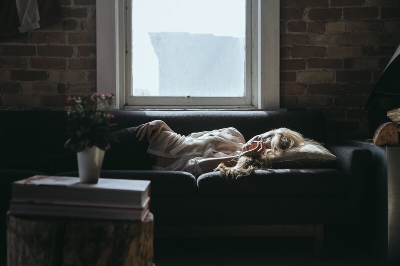Woman with depression and anxiety laying on her couch