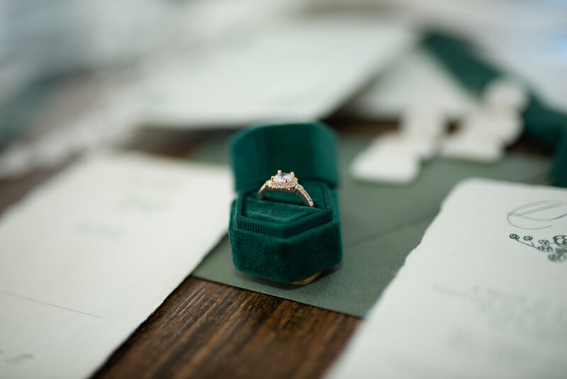 Diamond wedding wring in a green box surrounded by wedding day details