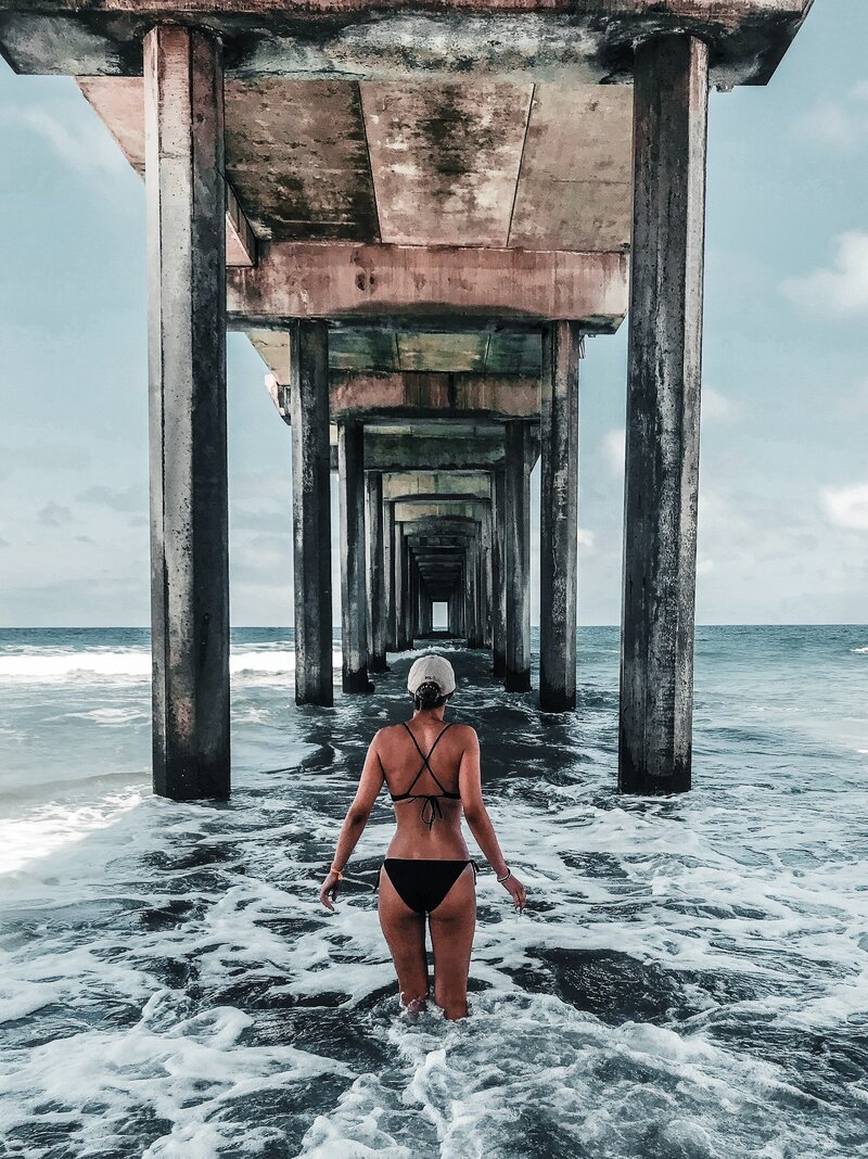 back-view-photo-of-woman-in-bikini-standing-below-wooden-2410770