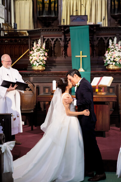Bride and groom kissing in front of the altar at church
