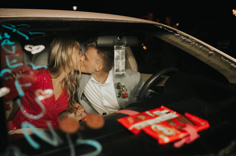 Newly married bride and groom kiss in their getaway car