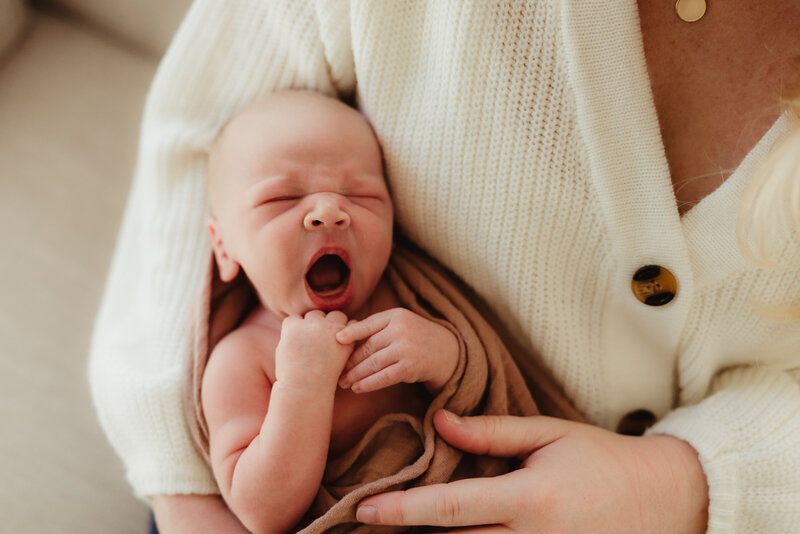 A new mother and father gaze down at their newborn daughter during their newborn photography session.