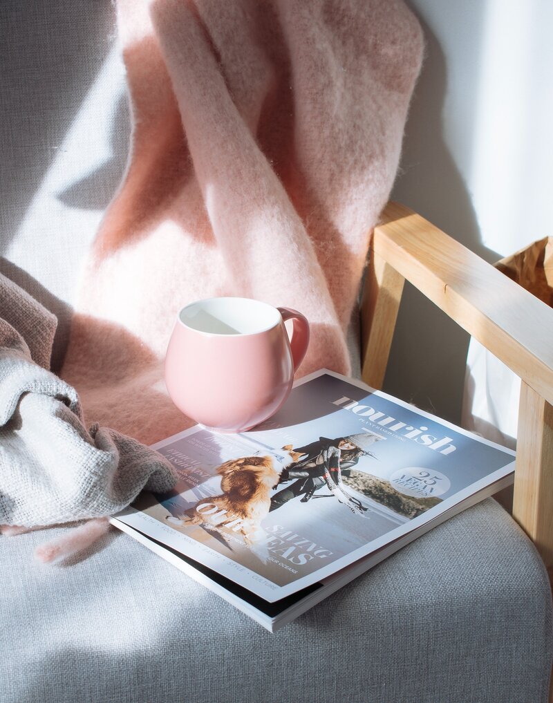 Pink mug on a magazine on a grey chair