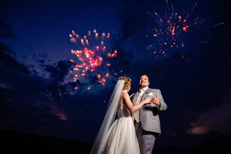Groom laughing while dancing the bride during their sunset fireworks