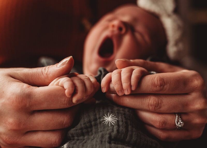 baby yawning in postpartum mother's arms