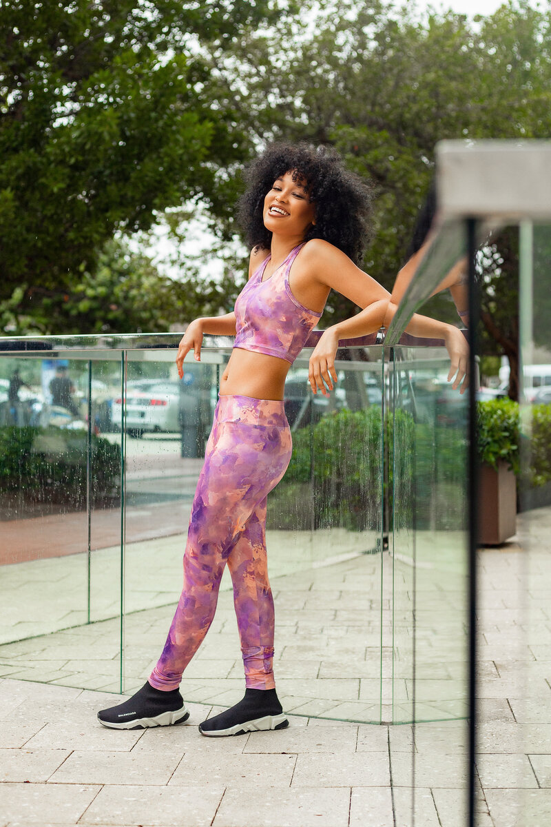 woman in pink leggings leaning against a glass wall