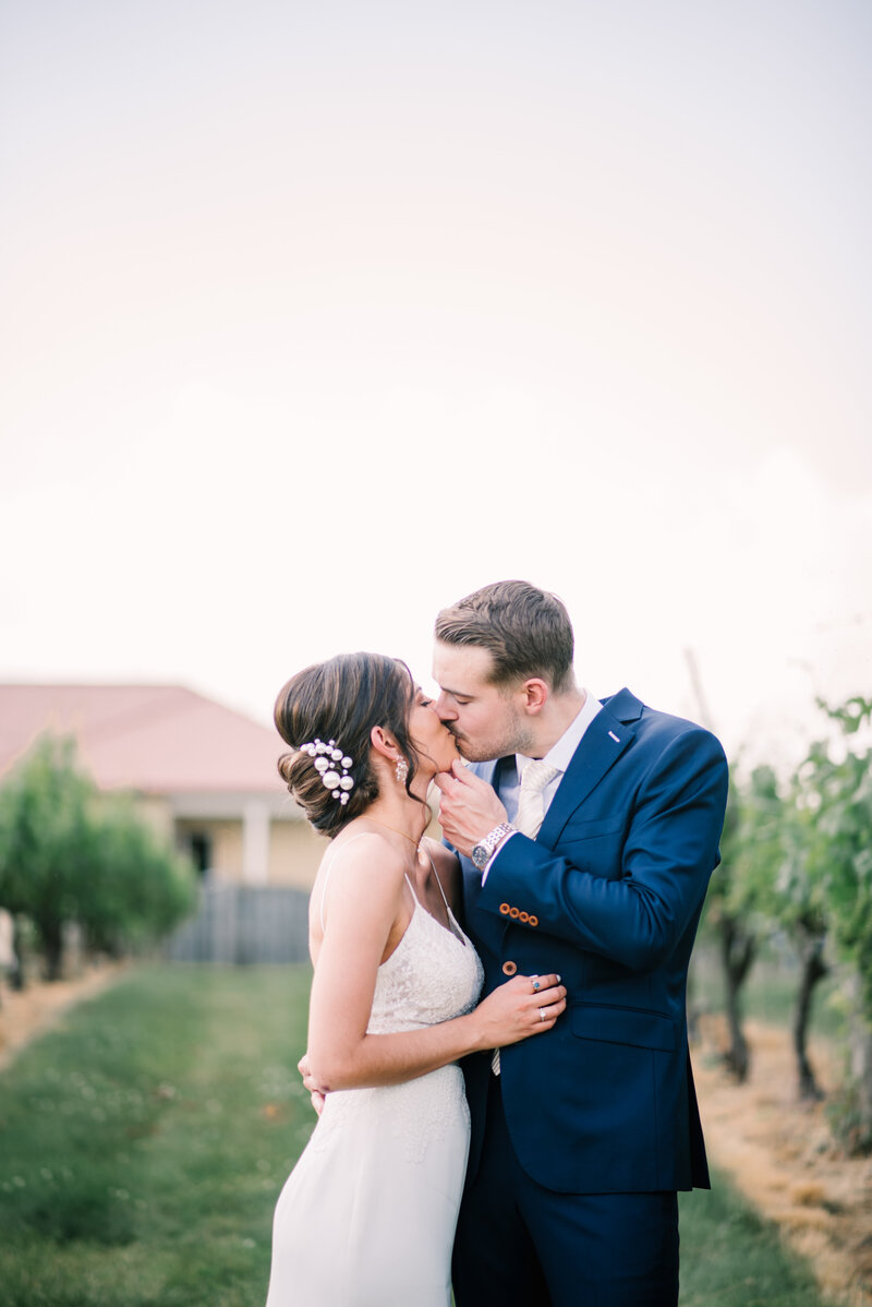 Bride and groom kiss in vineyard in Purcellville VA.
