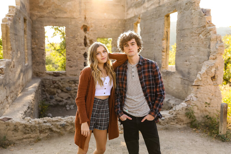 Styled senior portrait of a girl and guy at sunset in an abandoned stone building
