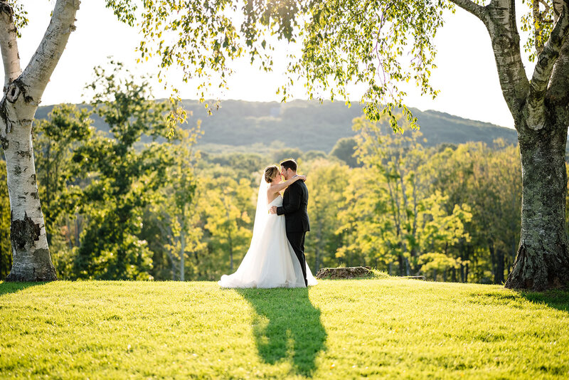 A bride and groom about to kiss while standing in a field
