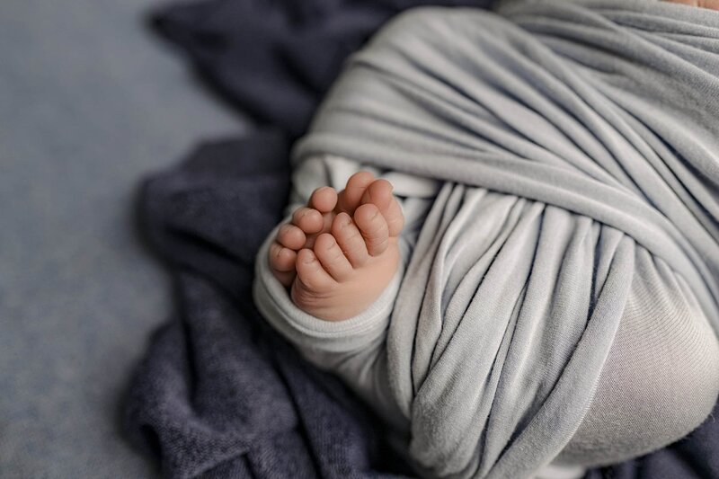 Close-up image of a baby's feet placed together where you can also see the newborn wrap