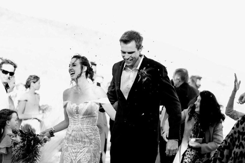 Newly-weds walking down the aisle with guests throwing confetti