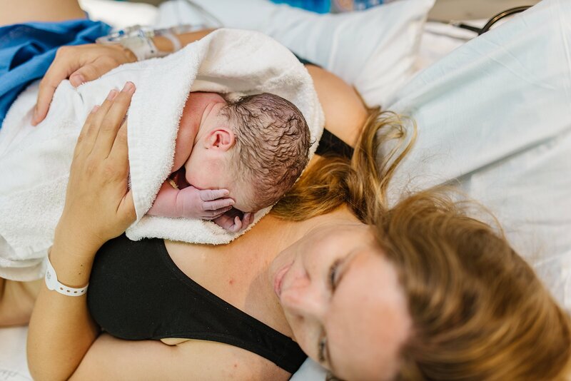 a mother holds her baby on her chest after giving birth