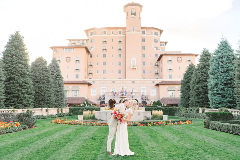 Newly married couple kissing in front of the iconic Broadmoor Hotel in Colorado Springs.