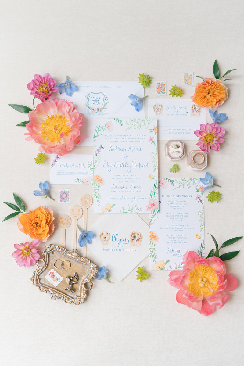 Summer wedding invitations with gorgeous spring blooms. Bright pink, yellow, and orange flowers with greenery.