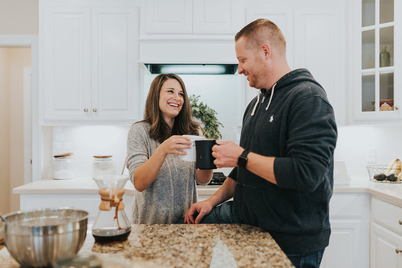 Two people sharing a light-hearted moment with mugs in a luxury kitchen.
